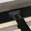 Close-up of a bed frame showing a black metal support bracket attached to a fabric-covered headboard, with wooden slats and a black strap across them.