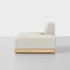 A modern, minimalist armless beige sofa module with a wooden base, shown in side view against a plain white and gray background.