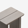 Close-up of the top corner of a light wood table with a visible central groove running lengthwise. The table has clean, modern lines and a smooth finish, set against a plain white background.