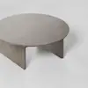 A round wooden coffee table with a smooth surface and sturdy, solid legs set against a plain, light-colored background.