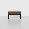 A minimal ottoman with a rectangular brown upholstered cushion and a dark wooden frame, set against a plain light grey background.