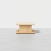 A minimalist wooden coffee table with a square top and bottom, featuring a central rectangular support, set against a plain light background.