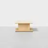 A minimalist wooden coffee table with a square top and bottom, featuring a central rectangular support, set against a plain light background.