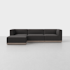A modern, dark gray sectional sofa with clean lines and a left-facing chaise, set on a light wood base, positioned in a minimalist, light-colored room.