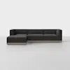 A modern, dark gray sectional sofa with clean lines and a left-facing chaise, set on a light wood base, positioned in a minimalist, light-colored room.