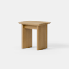 Minimalist wooden side table with a rectangular top and two wide, flat legs on either side, positioned against a plain white background.