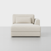 A modern, light beige upholstered chaise lounge with a backrest, a single right armrest, and a rectangular bolster pillow, set against a plain white background.