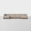 A modern, modular beige sectional sofa with low backs and arms, set on a wooden base, positioned on a smooth, light gray floor against a plain white background.