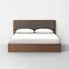 A modern wooden bed with a rectangular frame, gray fabric headboard, white bedding, and two white pillows, placed against a plain white wall on a light gray floor.
