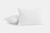 Two white pillows with a subtle checkered pattern are shown on a plain white background; one pillow is upright while the other lies flat behind it.