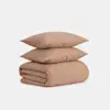 Two beige textured pillows stacked on top of a matching folded blanket, all set against a plain white background.