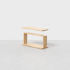A minimalist wooden table with a rectangular top floating above a simple open rectangular base, set against a plain light gray background.