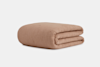 A neatly folded, textured, light brown blanket is displayed against a plain white background.