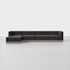 A modern, dark gray sectional sofa with clean lines and a low backrest, featuring a left-side chaise lounge and light wood base, set in a minimalistic white room.