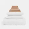 A neatly stacked bedding set with a white comforter and two white pillows at the bottom, topped with folded brown sheets and pillowcases, all arranged on a plain white background.