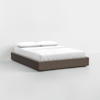 A modern, low-profile bed with a grey upholstered frame, white mattress, and two white pillows, set against a plain white background.