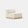 A modern armless lounge chair with a light beige upholstered seat and backrest, set on a simple wooden base, placed against a plain white background.