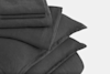 A neatly stacked set of dark gray bedding, including folded sheets and pillowcases, displayed on a plain white background.