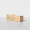 A modern, rectangular wooden dresser with four drawers sits on a light gray floor against a plain white background. The dresser has a minimalist design with no visible handles.