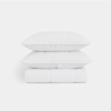 Two white pillows are stacked on top of a folded white comforter, all set against a plain white background.