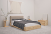Minimalist bedroom with a light wood bed frame, beige upholstered headboard, gray bedding, matching light wood nightstands, a potted branch, abstract wall art, and neutral-colored decor in a soft, pale room.