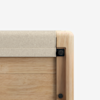 Close-up of the corner of a wooden table or furniture piece with a light wood finish, featuring a beige panel on top and visible black fasteners at the corner joints.