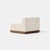 A modern armless lounge chair with a textured off-white cushion and a low wooden base, shown from the side against a plain white background.