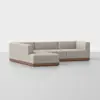 A modern L-shaped sectional sofa with light beige upholstery and a wooden base, set against a plain white background.