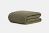 A neatly folded olive green quilted blanket with a subtle textured pattern, displayed on a plain light gray background.
