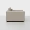Side view of a modern, light beige sofa with clean lines and square armrests, set against a plain white background. Two back cushions are visible.
