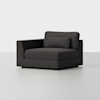 A modern, dark gray upholstered armchair with a wide seat, low backrest, and matching rectangular cushion, set against a plain white background.