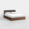 A modern bed with a dark upholstered headboard, white bedding, and a wooden platform base, set against a plain white background.