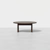 A round, dark brown wooden coffee table with thick legs, set against a plain white background.