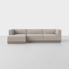 A modern, light beige L-shaped sectional sofa with clean lines and a low wooden base, set against a plain white background and floor.