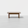 A simple rectangular wooden table with clean lines and a flat top, placed on a light gray floor against a plain white background.