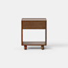 A modern wooden nightstand with a single drawer and an open lower shelf, standing on four short cylindrical legs against a plain white background.
