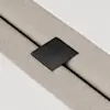 A close-up of a textured beige fabric strap secured by a black rectangular metal clip engraved with the word THUMA, set against a white background.