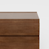 A close-up view of a modern wooden dresser with a smooth finish, showing the top surface and upper drawers against a plain white background.