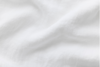 A close-up of a soft, white fabric with gentle folds and subtle texture, creating a smooth and airy appearance.