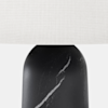 Close-up of a lamp with a white fabric shade and a black marble base featuring white veining.