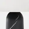 Close-up of a lamp with a white fabric shade and a black marble base featuring white veining.