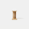 A minimalist wooden stool with a rectangular top and base, connected by a central vertical support, placed on a smooth, light grey surface against a plain white background.