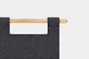 A close-up of a wooden rod threaded through two fabric loops on a piece of dark gray felt material, set against a plain white background.
