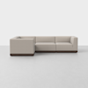 A modern L-shaped sectional sofa with light beige upholstery and a dark wooden base, placed on a light gray floor against a plain white background.