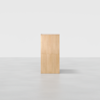 A light wooden rectangular pedestal with clean lines stands on a smooth, light gray floor against a plain white background.