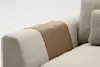 Close-up of a modern beige fabric sofa with a textured surface, featuring a brown leather strip draped over the armrest. The background is plain and minimalistic.