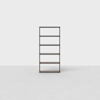 A minimalist, dark wooden bookshelf with five shelves stands empty against a plain white background on a light gray floor.