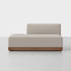 A modern, minimalist beige chaise lounge with a low, rectangular wooden base and an off-center backrest, set against a plain white background.