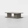 A minimalist rectangular coffee table in light wood with a thick top, open sides, and a wide base, set against a plain white background.