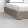 A close-up view of a modern bed with a wooden platform frame and white bedding, positioned on a light gray floor.